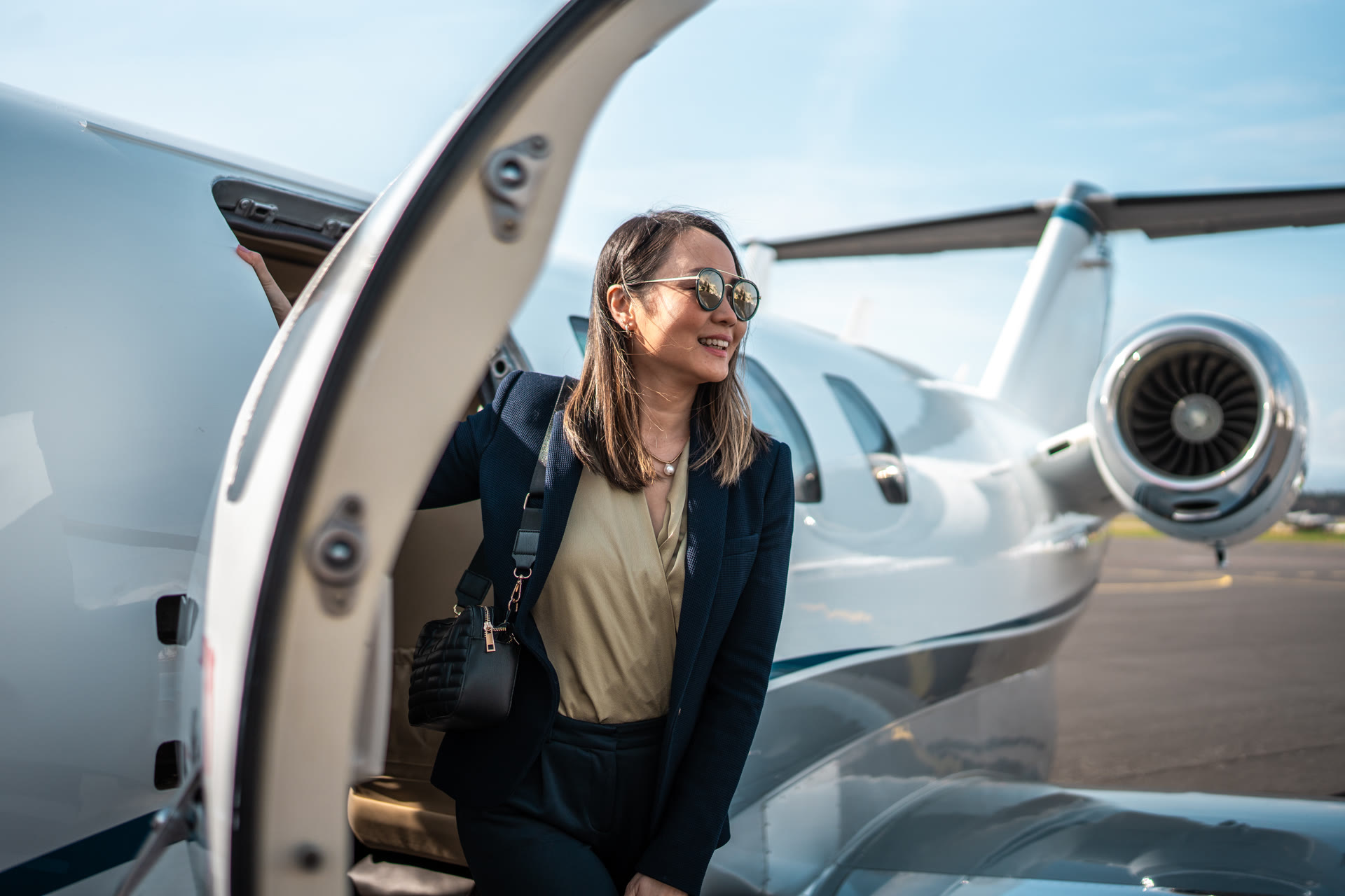 A traveler stepping down from a private jet onto the tarmac at golden hour