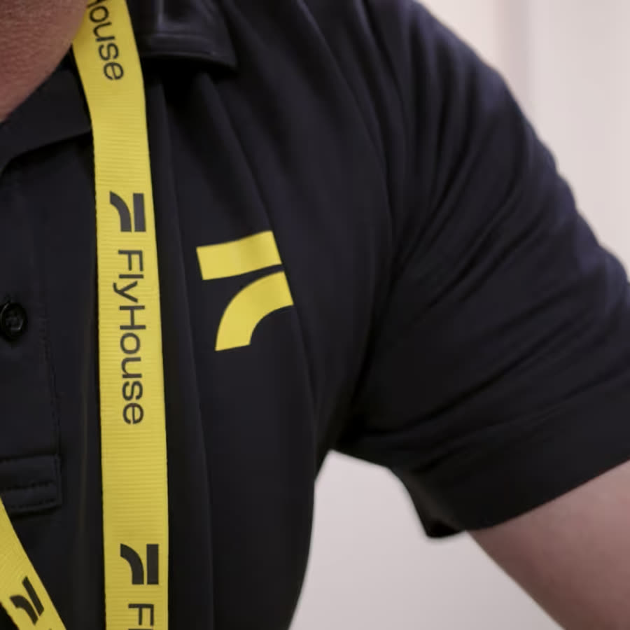 A FlyHouse crew member in branded polo and lanyard